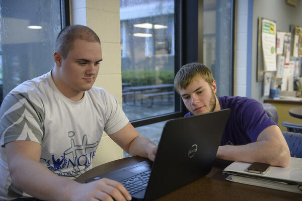 photo of two students looking at a laptop